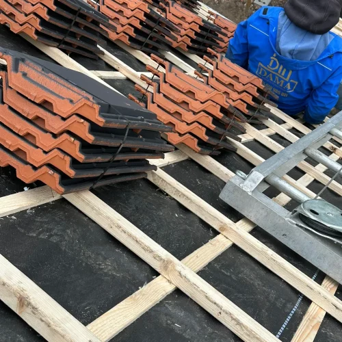 Rode dakpannen gestapeld op nieuwe panlatten, klaar om te leggen in Barneveld