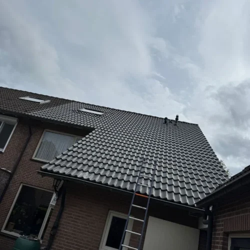 Nieuw antraciet pannendak op een bakstenen woning met ladder tegen de gevel in Barneveld