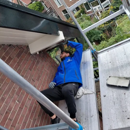 Dakdekker op een steiger werkt aan de onderzijde van een dakrand in Barneveld
